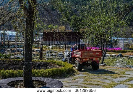Hwanggan, South Korea; April 14, 2020: Red, Dirty Farm Utility Vehicle Parked In Front Of Pond At No