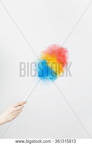 Woman's Hand Holds Brush To Clean Dust On Grey Background