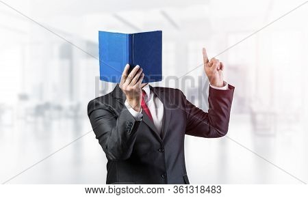 Businessman Covered His Face With Book And Finger Pointing Up. Portrait Of Man In Business Suit Stan