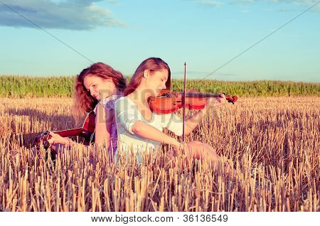 To unge kvinder spiller Guitar og Violin udendørs. Split Toning.