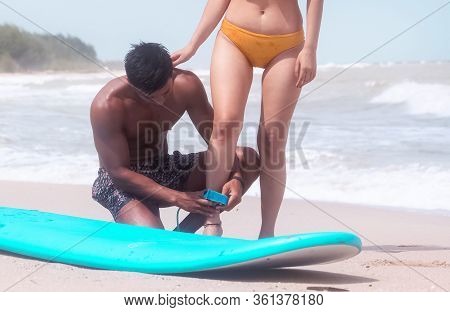 The Beautiful Woman Wearing Black Swimming Suit And Yong Handsome Man Posing Beside Serf Board On Th