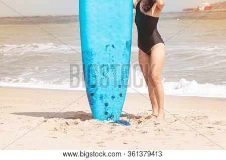 The Beautiful Woman Wearing Black Swimming Suit Posing Beside Serf Board On The Beach,with Enjoy And