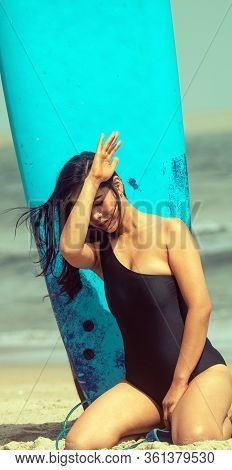 The Beautiful Woman Wearing Black Swimming Suit Posing Beside Serf Board On The Beach,with Enjoy And