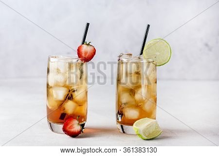 Glasses Of Cold Citrus And Strawberry Ice Tea On Light Gray Background Decorated With Ripe Lime And 