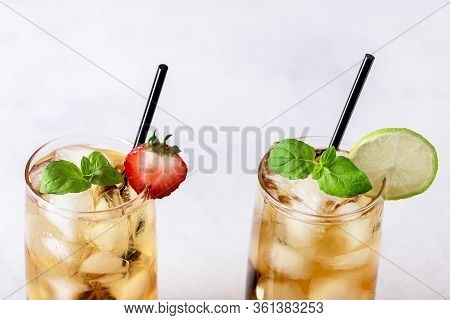 Glasses Of Cold Citrus And Strawberry Ice Tea On Light Gray Background Decorated With Ripe Lime And 