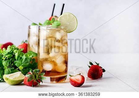 Glasses Of Cold Citrus And Strawberry Ice Tea On Light Gray Background Decorated With Ripe Lime And 