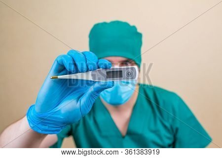 Thermometer In Doctors Hand On Yellow Background. Copy Space Temperature Field. Selective Focus