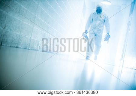 corona virus concept. male scientist doctor in latex biochemical protective suit walking in laboratory coridor holding children plush toys