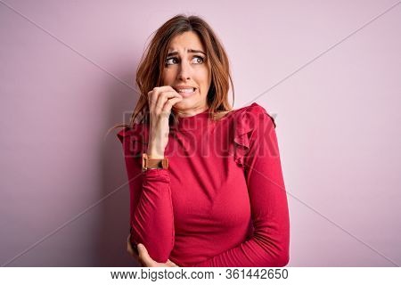 Young beautiful brunette woman wearing casual sweater stnding over pink background looking stressed and nervous with hands on mouth biting nails. Anxiety problem.