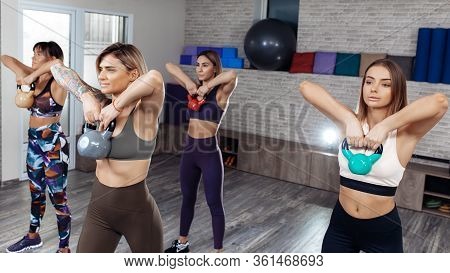 Group Of Four Young Sporty Girls Workout With Kettlebells In Fitness Class. Functional Resistance Tr
