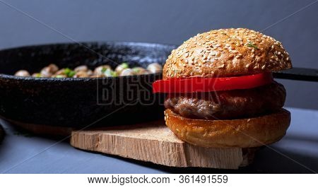 Burger With A Juicy Cutlet Tender Bun And Champignon Mushrooms In A Castiron Pan On A Wooden Rustic 
