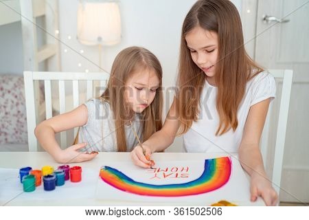 Two Sisters Drawing On A White Sheet Rainbow And Write Stay Home. Flashmob Chasetherainbow.