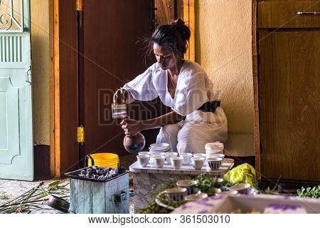 Axum, Ethiopia - Feb 09, 2020: Young Woman In Traditional Clothing Is Preparing A Coffee Ceremony. T