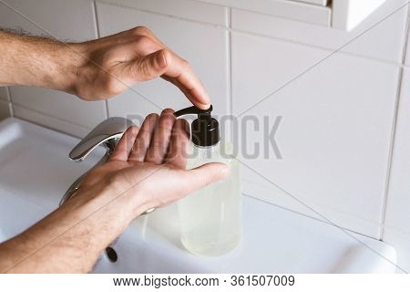 Man Cleaning His Hands Using Liquid Disinfectant Soap And Water In Bathroom.