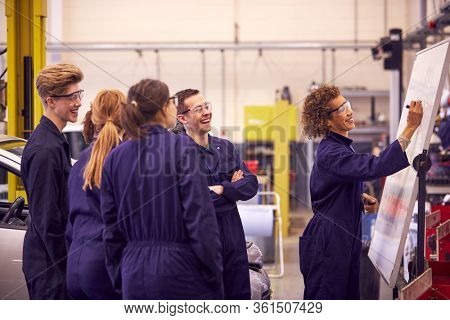 Female Tutor By Whiteboard With Students Teaching Auto Mechanic Apprenticeship At College
