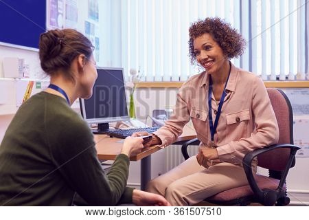 Female College Student Meeting With Campus Counselor Discussing Mental Health Issues
