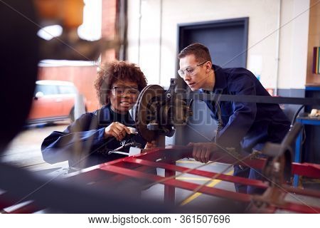 Male And Female Students Working On Car Brakes On Auto Mechanic Apprenticeship Course At College
