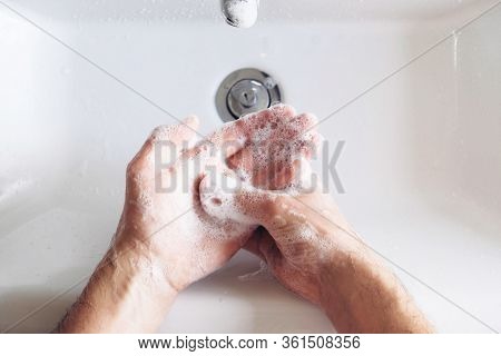 Man Cleaning His Hands Using Liquid Disinfectant Soap And Water In Bathroom.