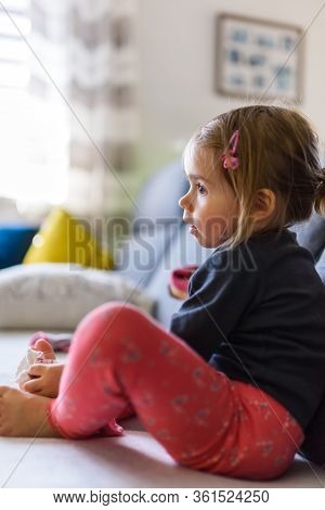 Two Year Old Girl With Big Eyas Portrait Sitting On Couch Watching Tv, Indoor Shoot With Natural Lig