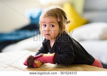 Two Year Old Girl With Big Eyas Portrait Looking At Camera With Socks On Her Hands, Indoor Shoot Wit
