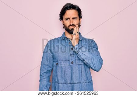Young handsome hispanic bohemian man wearing hippie style over pink background touching mouth with hand with painful expression because of toothache or dental illness on teeth. Dentist
