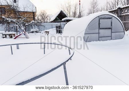 Winter, Snow, Frost In The Garden. Childish Snow-covered Slide In The Garden. Trampoline On White Sn