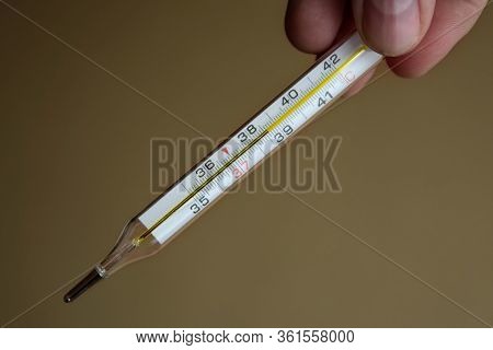 Medical Thermometer For Measuring Body Temperature In The Hand In The Foreground. High Body Temperat