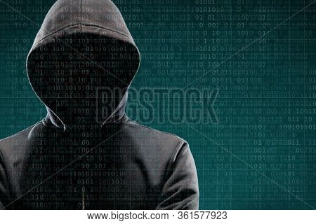 Computer hacker in mask and hoodie over abstract binary background. Obscured dark face. Data thief, internet fraud, darknet and cyber security.