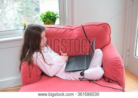 Preteen Girl Enjoyes Homeschooling Or Video Call In Comfy Pajama And Cozy Sofa Chair. Remote Educati