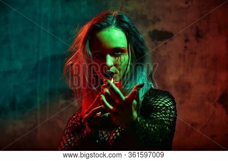 Close Up Portrait Of Beautiful Sexy Witch With Halloween Makeup. Red And Black Face Painting. Chain 