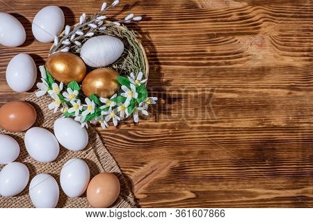 Easter Eggs In Basket Filled With Straw And Yellow Flowers And Willow On Wooden Rustic Vintage Backg