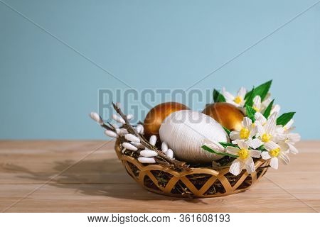 Easter Eggs In Basket Filled With Straw And Yellow Flowers And Willow. Preparation For Holiday. East