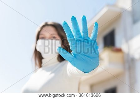 Stay At Home. Covid-19 Quarantine. A Girl In Protective Mask And Gloves Blocks Corona Virus. Social 