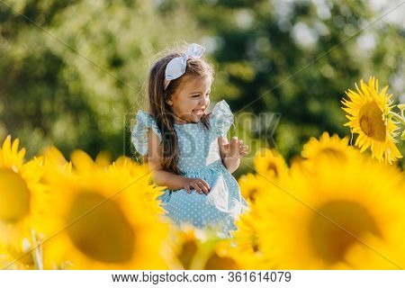 Little Cheerful Girl In A Field Of Yellow Sunflowers. Child And Sunflower, Summer, Nature And Fun. S