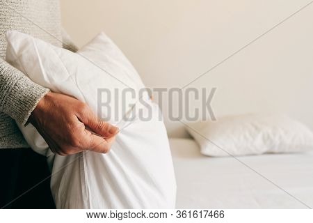 closeup of a young caucasian man introducing a pillow into a white pillow case as he is making the bed
