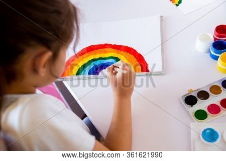 Stay At Home Due Covid - 2019 Pandemic Concept. View From Above. Little Girl Draws A Rainbow At The 