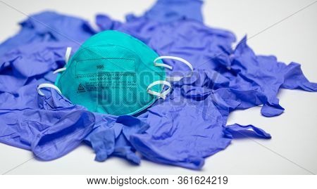 A Turquoise N95 Particulate Respirator And Surgical Mask On Top Of Many Medical Gloves.