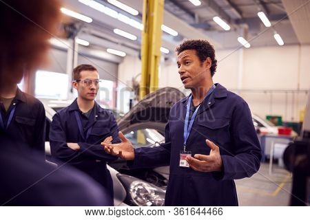 Male Tutor With Students Teaching Auto Mechanic Apprenticeship At College