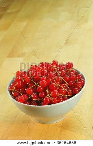 ผลไม้ currant แดงในชามบนโต๊ะไม้