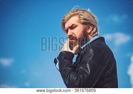 Brutal Man With Beard On Blurry Background Sky Smoking And Loking In Kamera.