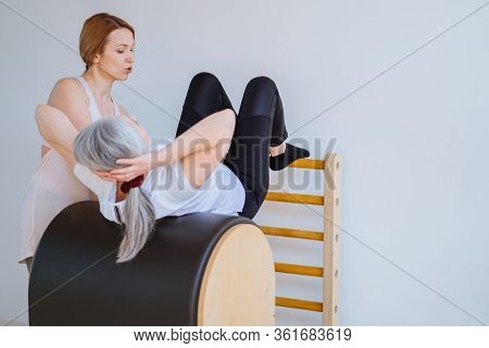 Woman Exercising With Instructor In Pilates Studio Or Gym. Healthy Lifestyle For Elderly People Conc