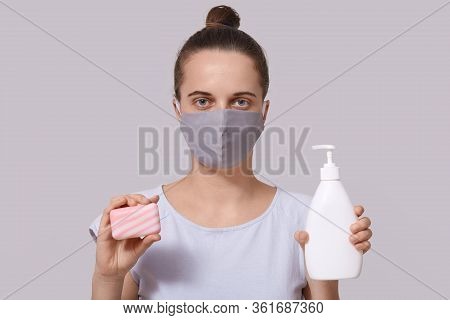 Closeup Portrait Of Young Woman Wearing White Casual T Shirt And Protective Face Mask, Holds In Hand
