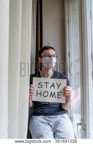 Man Sitting On Windowsill With Nameplate At Selfisolation