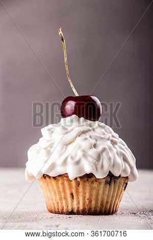Muffins And Cupkake With Whipped Cream Decorated With Strawberry On Top On Gray Background.