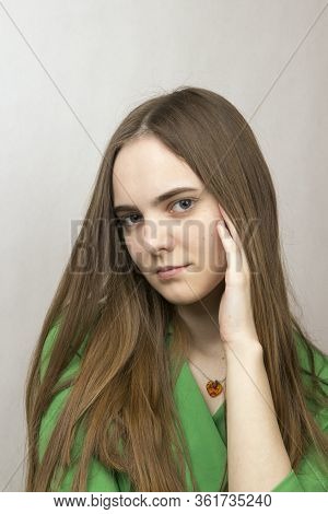 Close-up Portrait Of A Blonde Long-haired Romantic Girl With Big Gray Blond Eyes In A Green Dress