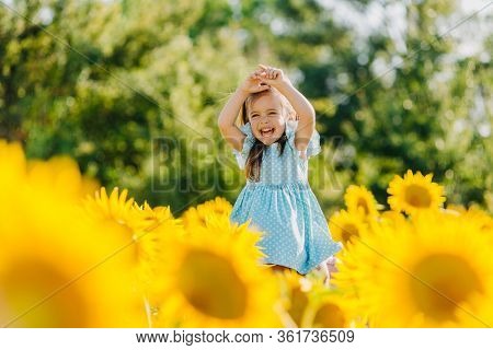 Little Cheerful Girl In A Field Of Yellow Sunflowers. Child And Sunflower, Summer, Nature And Fun. S