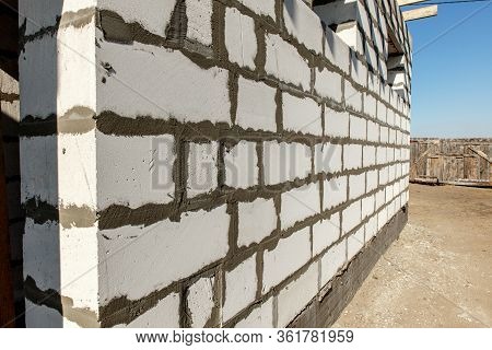 Building Site Of A House Under Construction. Corner Unfinished House Walls Made From White Aerated A