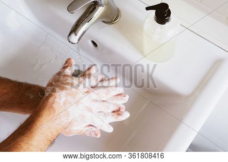 Man Cleaning His Hands Using Liquid Disinfectant Soap And Water.
