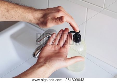 Man Cleaning His Hands Using Liquid Disinfectant Soap And Water.