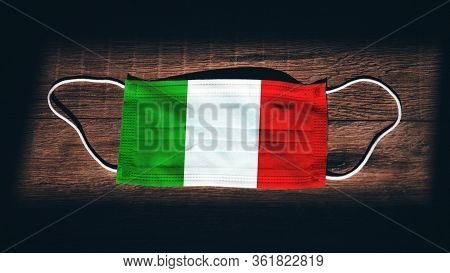 Italy National Flag At Medical, Surgical, Protection Mask On Black Wooden Background. Coronavirus Co